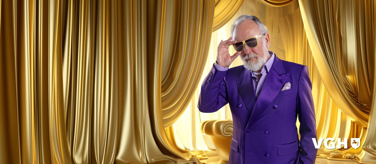 älterer Herr mit Sonnenbrille steht in einem goldenen Zimmer